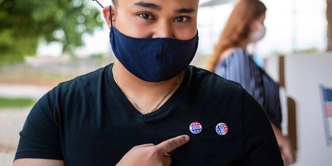 masked-voter-pointing-to-buttons-666×333-1